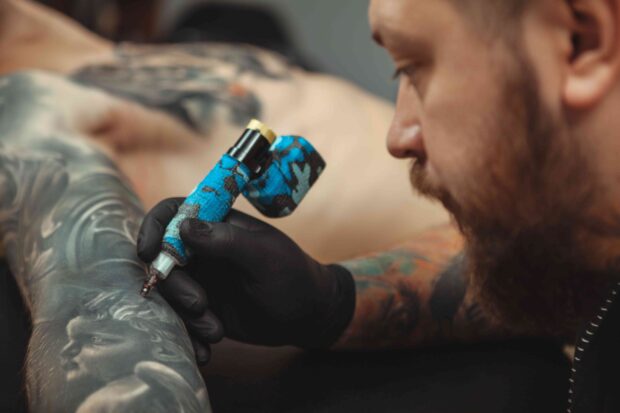 Tätowierer tätowiert ein Tattoo.